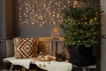 Wooden bench stand in corner of room. Fir in black basket stand on it and firewood lays under it
