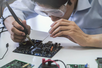 Close up of the hand men hold tool repairs electronics manufacturing Services, Manual Assembly Of Circuit Board Soldering.