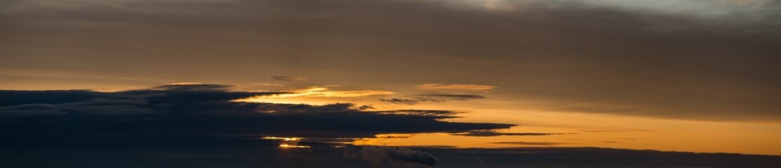 Fototapeta na wymiar Fantastic dark thunderclouds at sunrise, wide panorama