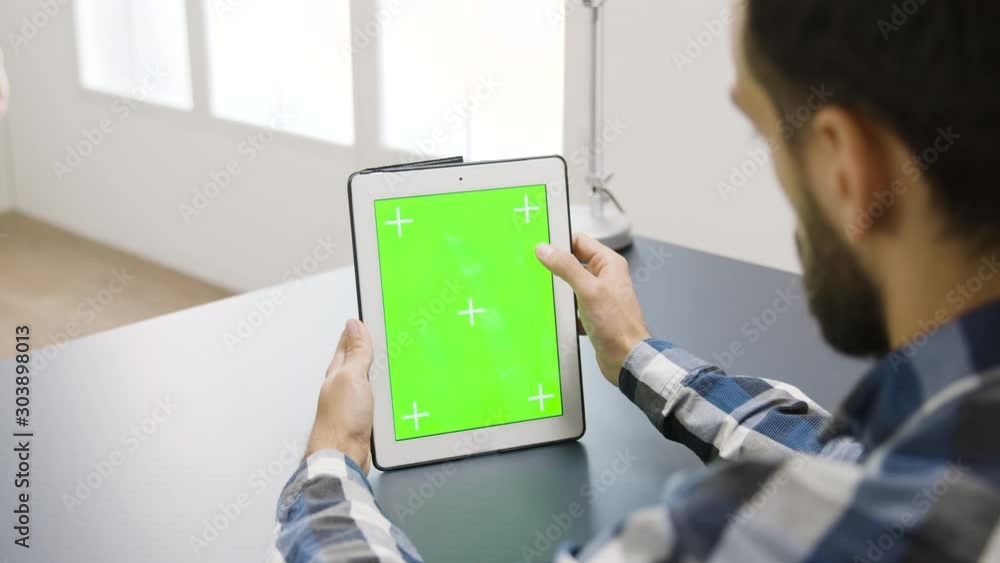 Poster man touching the screen of a digital tablet pc with green mock-up on it