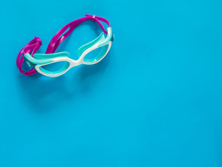 Swimming pool glasses on blue background with copy space