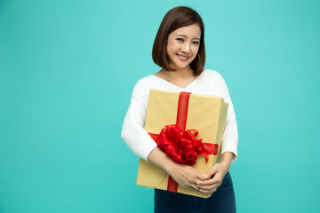 Fototapeta premium Happy beautiful asian woman smile with gold gift box isolated on light green background. Teenage girls in love, Receiving gifts from lovers. New Year, Christmas and Valentines Day concept