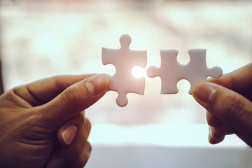 Closeup hand of business people connecting jigsaw puzzle with sunlight effect, Business solutions and represent team support and help concept, success and strategy concept - obrazy, fototapety, plakaty