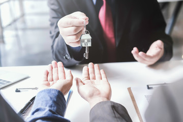 real estate agent holding house key to his client after signing contract,concept for real estate,...