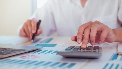 asian businessman or accountant working pointing graph discussion and analysis data charts and graphs and using a calculator to calculate  numbers.Business finances and accounting concept