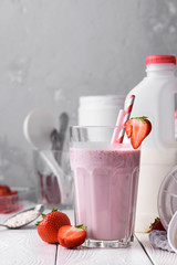 Strawberry protein shake on a white wooden background. Fresh milkshake with strawberries on a light table. A glass of strawberry smoothie.