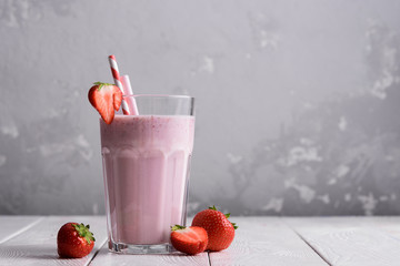 Strawberry protein shake on a white wooden background. Fresh milkshake with strawberries on a light table. A glass of strawberry smoothie.