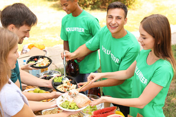 Young volunteers giving food to poor people outdoors