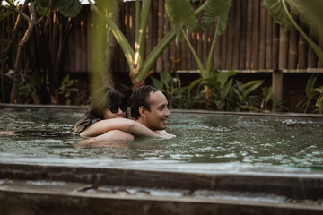 Happy couple hugging in a swimming pool when vacation at resort