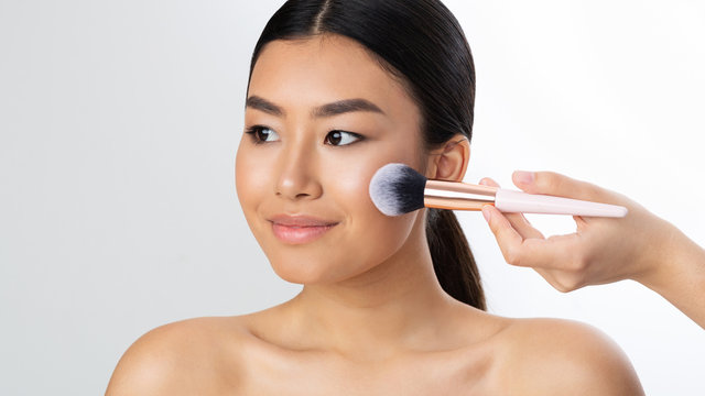Makeup artist applying blush on cheeks with brush