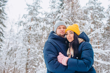 young couple in love walks in the winter forest. active winter holidays. A couple hugs and laughs on a background of a snowy forest. Closeup portrait of a guy and a girl in a snowy forest.