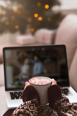 Female with cup of hot chocolate watching on laptop