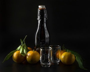 Fototapeta na wymiar Background with liquor bottle, glasses and tangerines