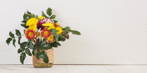 Bouquet of flowers in a vase on a white table, copy space banner.