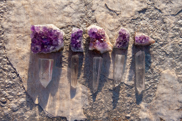 Amethyst and Quartz Crystal stones casting shadows and light on gray stone slab.  Natural object...