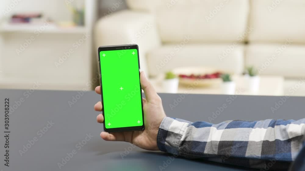Poster zoom in parallax shot of man holding a green screen phone on the table