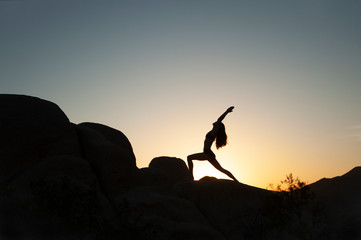 Yoga woman silhouette in the desert sunset. 