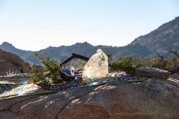Crystal altar on Shipibo sacred indigenous textile in the Mojave Desert with a mountain landscape.