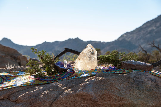 Crystal altar on Shipibo sacred indigenous textile in the Mojave Desert with a mountain landscape.