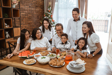 asian family fun having lunch with friends in diningroom together on christmas celebration