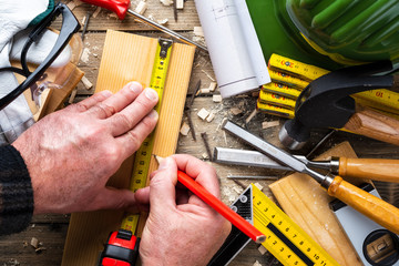 Top view. Carpenter with pencil and the meter marks the measurement on a wooden board. Construction industry, do it yourself. Wooden work table.