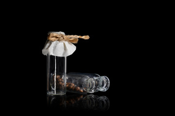 Fototapeta na wymiar Three small glass vial with brown pills on the black. Vials are tied with twine. 