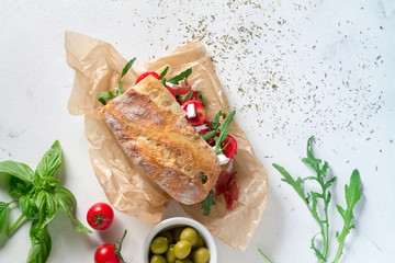 Sandwich with jamon, cheese, tomatoes and arugula on a white background