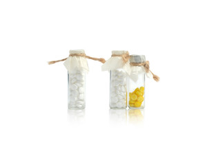 Three small glass vials of white and yellow pills tied with twine. On white background.