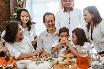 asian family fun having lunch with friends in diningroom together on christmas celebration