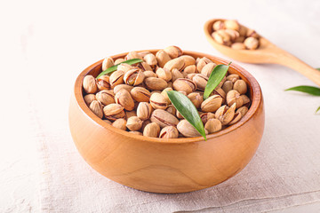 Bowl with tasty pistachio nuts on table