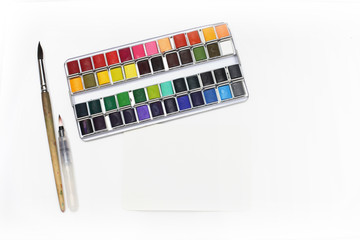 Box with watercolors and brush on a light copy space gray background..Flat lay.  Top view..