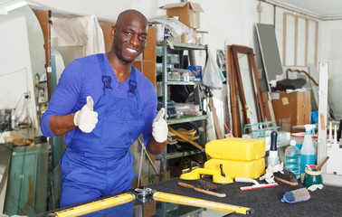 Fototapeta na wymiar satisfied African-American workman in blue overalls