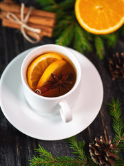 Mug of black tea with orange and cinnamon. Winter hot drink on wooden table