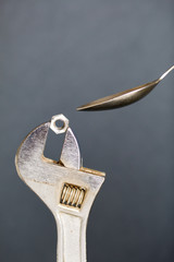 Adjustable wrench with nut and spoon. Imitation of spoon feeding.