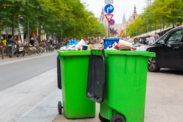 Green garbage can on sidewalk, european city