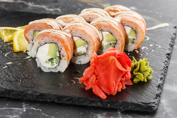 Sushi Rolls with flamed salmon, cucumber and Cream Cheese inside on black slate isolated on black marble background. Philadelphia roll sushi with cucumber. Sushi menu. Horizontal photo.