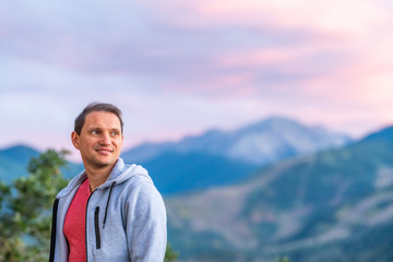 Aspen, Colorado mountains colorful purple blue twilight sunset blurry background view and happy young man standing looking