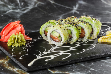 Green dragon sushi roll with salmon, cucumber and avocado. Japanese food. Traditional asian rice sushi healthy seafood. Black marble background. Horizontal photo.