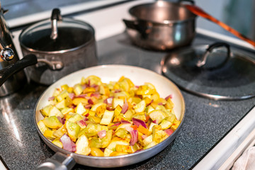 Cooking frying pan and homemade chopped yellow summer zucchini squash vegetables closeup in kitchen...