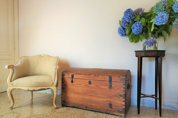 old wooden chest, antique armchair, vase with blue flowers