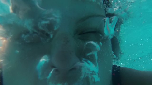 Woman underwater in the pool with her eyes closed.
