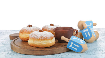 Donuts for Hanukkah and dreidels on table against white background