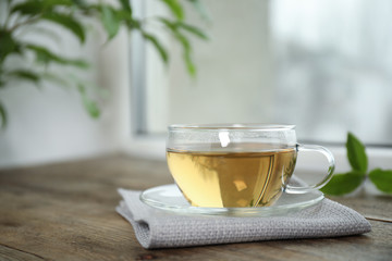 Tasty hot green tea in cup on wooden table