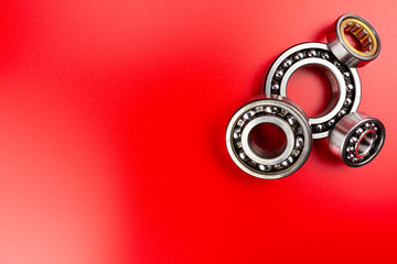 Ball bearing lying on a red background with copy space on the left side. Flat view from above.