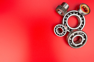 Ball bearing lying on a red background with copy space on the left side. Flat view from above.