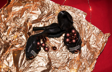 Black holiday shoes with fringe and rhinestones lie and stand with New Year's brown balls, garlands...