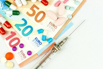 Financing of health care. Medicine, finance, health care and drug trafficking - medical pills or drugs and euro cash money on white background.