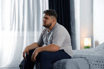 Depressed overweight man on bed at home