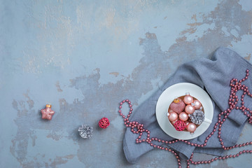 Obraz na płótnie Canvas Pink christmas balls and natural cone in the white tea set on grey napkin