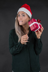 young blond girl with Santa hat and gift present ist surprised an smiles